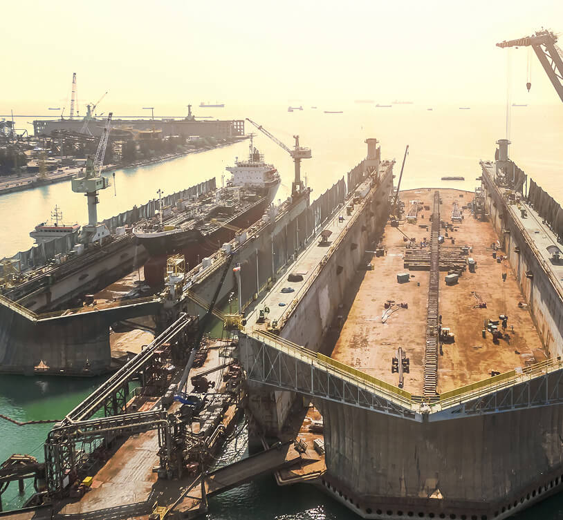Shipyard dry dock with cargo vessels under repair, supporting shipbuilding and marine valve applications in Singapore